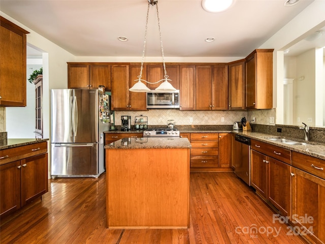 kitchen with pendant lighting, sink, dark stone countertops, stainless steel appliances, and a kitchen island