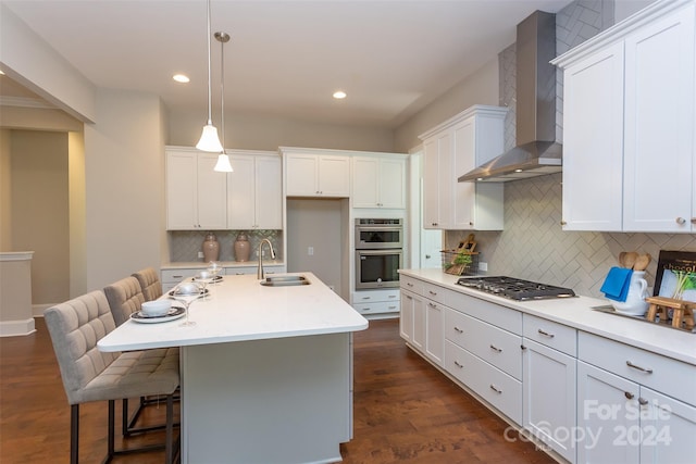 kitchen featuring appliances with stainless steel finishes, sink, backsplash, dark hardwood / wood-style floors, and wall chimney exhaust hood