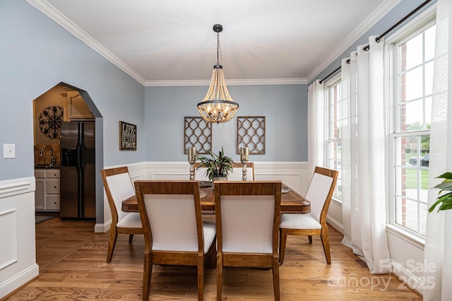 dining room with a notable chandelier, sink, ornamental molding, and light hardwood / wood-style flooring