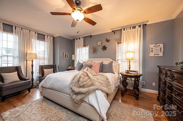 bedroom featuring ceiling fan, multiple windows, and hardwood / wood-style flooring