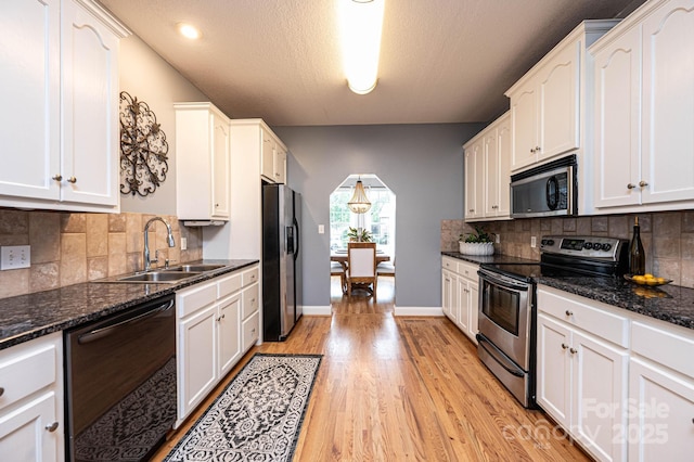 kitchen featuring appliances with stainless steel finishes, sink, white cabinetry, and dark stone counters