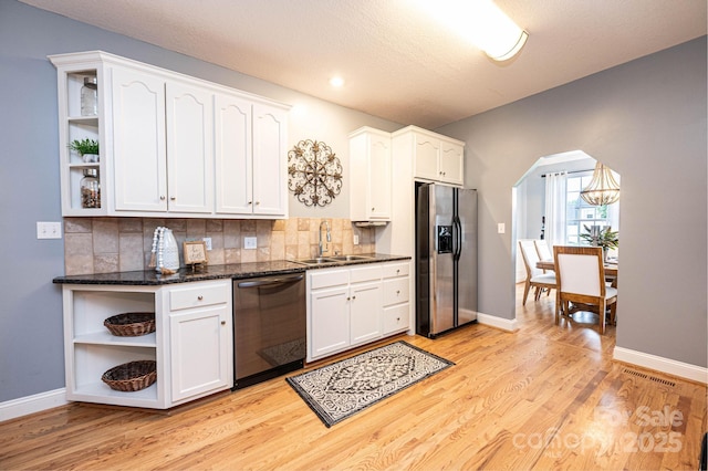 kitchen featuring white cabinetry, black dishwasher, sink, stainless steel fridge, and light wood-type flooring