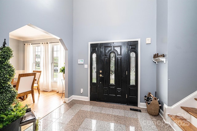 entryway with ornamental molding and a towering ceiling