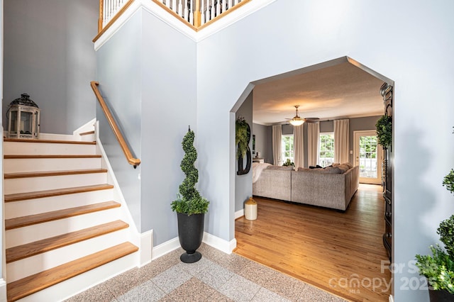 stairs featuring ceiling fan and a towering ceiling