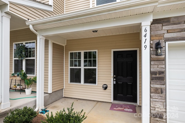 view of exterior entry with a garage and a porch