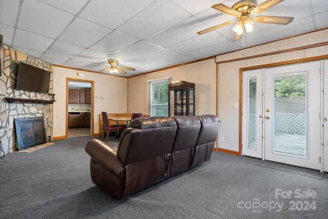 carpeted living room featuring a fireplace, a paneled ceiling, ornamental molding, and ceiling fan