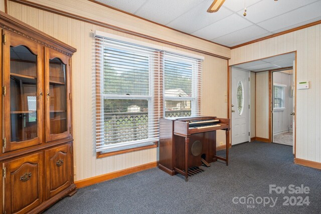 office space featuring ceiling fan, dark colored carpet, crown molding, and a paneled ceiling