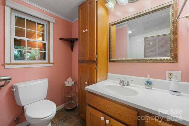 bathroom with tile patterned floors, crown molding, toilet, and vanity