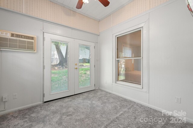 empty room with a wall mounted AC, light carpet, ceiling fan, and french doors