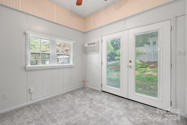 carpeted spare room with plenty of natural light, a wall unit AC, french doors, and ceiling fan