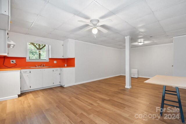 basement featuring light hardwood / wood-style floors, a drop ceiling, ceiling fan, and sink