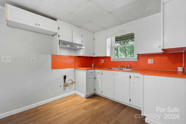 kitchen featuring sink, a paneled ceiling, wood-type flooring, and white cabinets