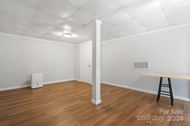 basement with wood-type flooring and a paneled ceiling