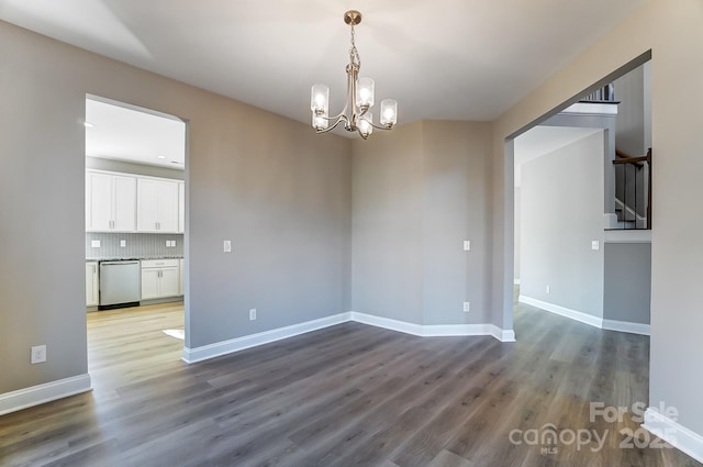 unfurnished room with wood-type flooring and a notable chandelier