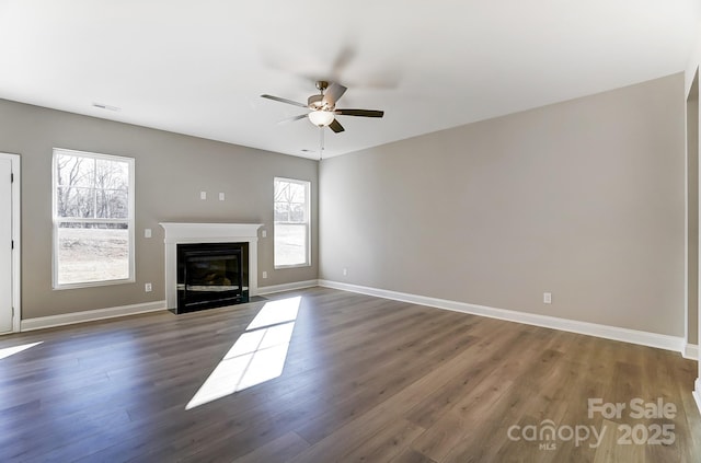 unfurnished living room featuring ceiling fan, plenty of natural light, and dark hardwood / wood-style flooring