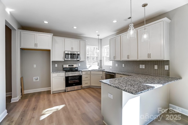 kitchen with light hardwood / wood-style floors, kitchen peninsula, appliances with stainless steel finishes, decorative light fixtures, and white cabinets