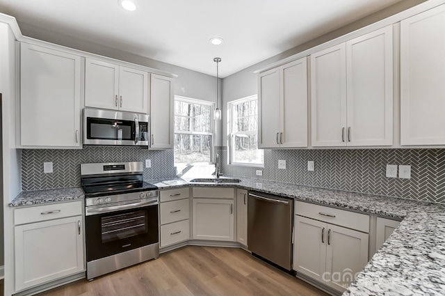 kitchen featuring sink, hanging light fixtures, white cabinets, and stainless steel appliances