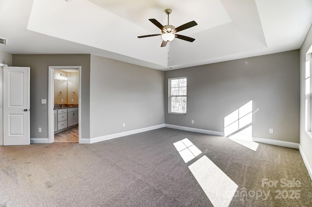 interior space featuring ceiling fan, light colored carpet, and a tray ceiling