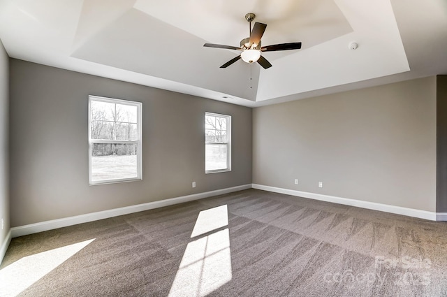 carpeted spare room with ceiling fan and a tray ceiling