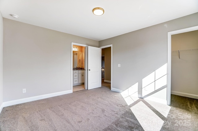 unfurnished bedroom with light colored carpet, a closet, a spacious closet, and connected bathroom