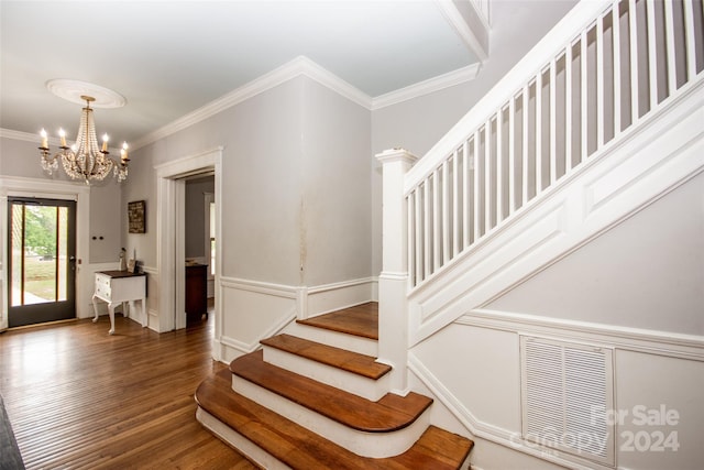 staircase featuring crown molding, wood-type flooring, and a chandelier