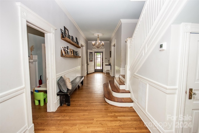 hallway featuring an inviting chandelier, ornamental molding, and light hardwood / wood-style floors