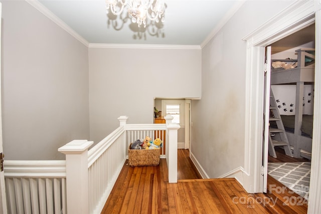 hall featuring hardwood / wood-style floors, crown molding, and a notable chandelier