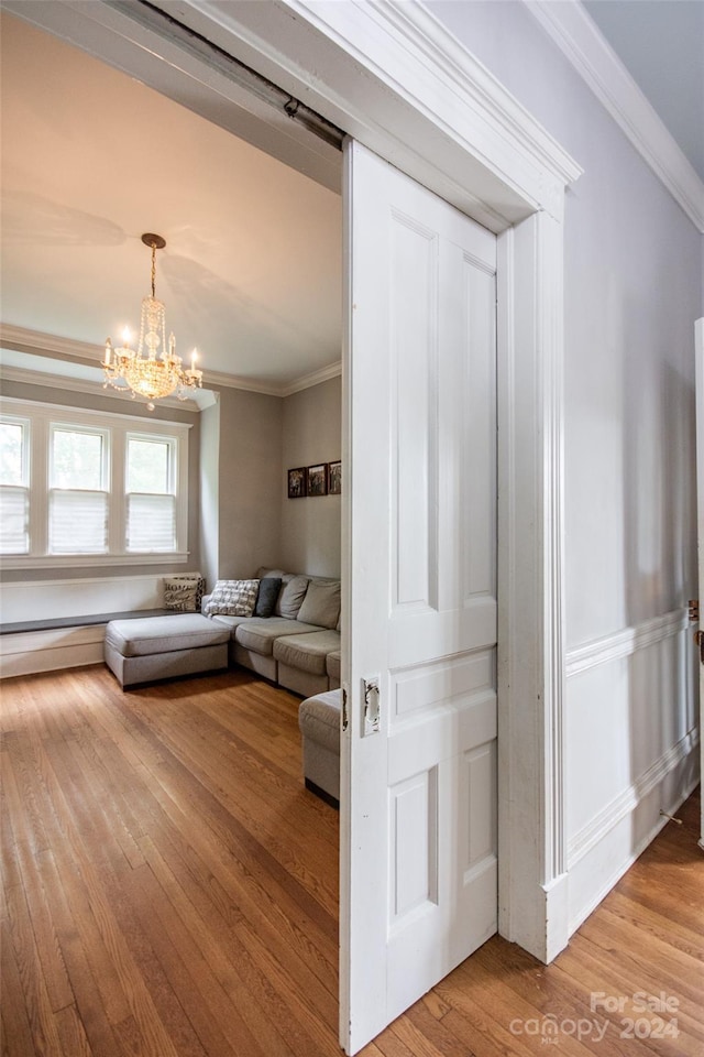 living room with hardwood / wood-style flooring, ornamental molding, and a chandelier