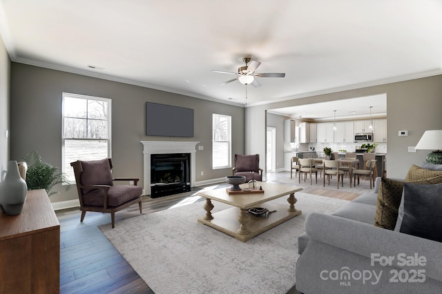 living room with ornamental molding, ceiling fan, and light hardwood / wood-style floors