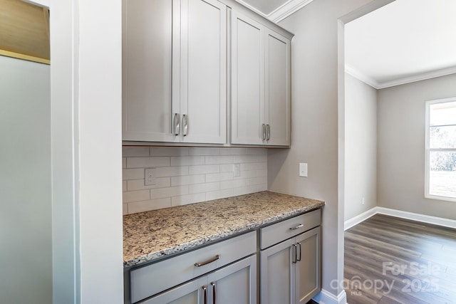 kitchen featuring decorative backsplash, light stone countertops, gray cabinets, and ornamental molding