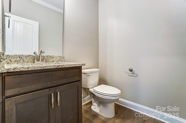 bathroom with hardwood / wood-style floors, toilet, vanity, and ornamental molding