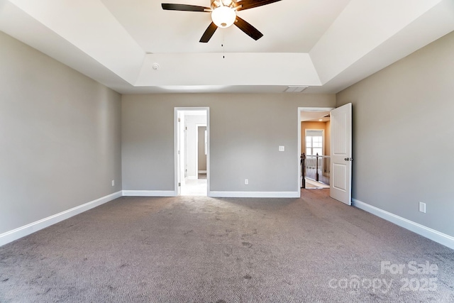 unfurnished bedroom featuring ceiling fan, carpet, and a raised ceiling