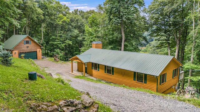 rustic home featuring metal roof, a garage, an outdoor structure, faux log siding, and a chimney