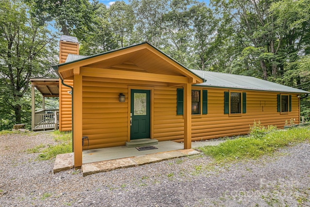 rustic home featuring metal roof, a chimney, and faux log siding