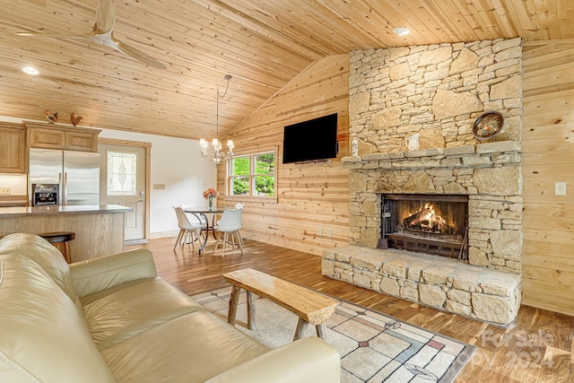 living room with a stone fireplace, wooden ceiling, light wood-style flooring, wooden walls, and vaulted ceiling