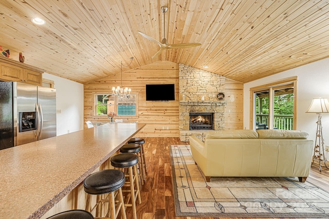 unfurnished living room featuring wooden ceiling, wood walls, a fireplace, vaulted ceiling, and light wood-type flooring