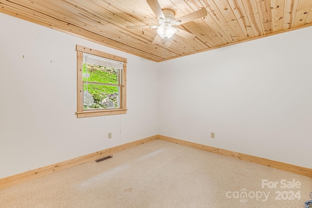 empty room with carpet floors, visible vents, a ceiling fan, wood ceiling, and baseboards