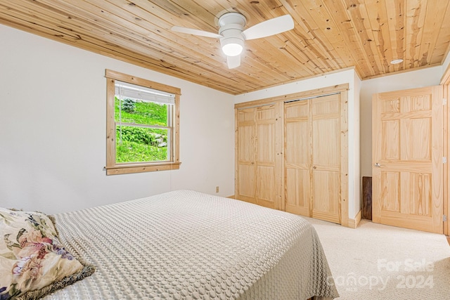 carpeted bedroom with a closet, wood ceiling, and a ceiling fan