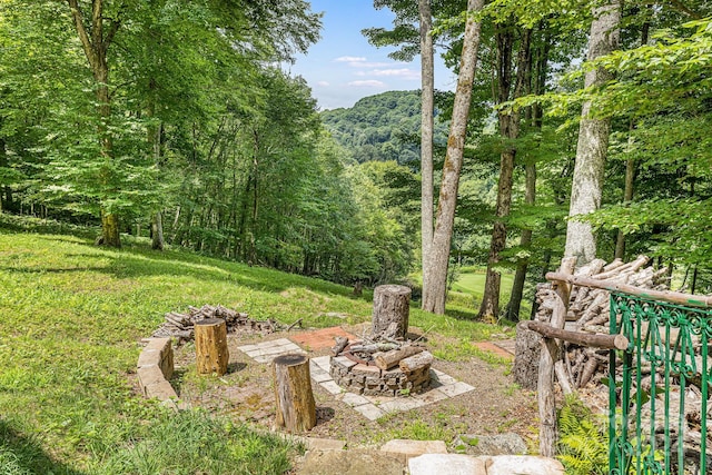 view of yard featuring an outdoor fire pit and a wooded view