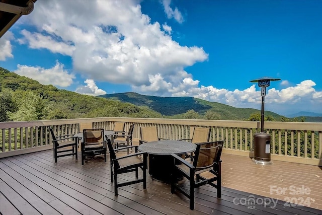 deck with a mountain view and outdoor dining area