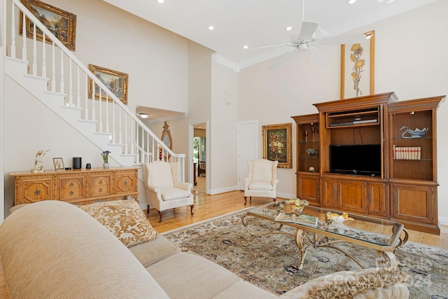 living room featuring ceiling fan, light wood-type flooring, and a towering ceiling