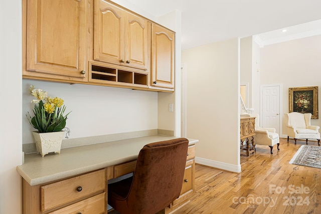 office space with light hardwood / wood-style flooring, built in desk, and ornamental molding