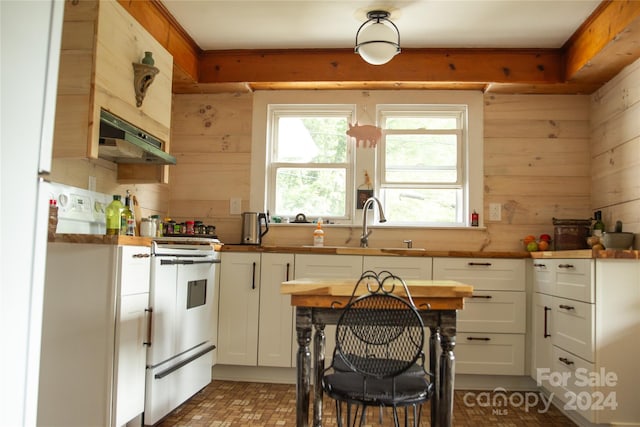 kitchen featuring wooden walls, sink, white cabinetry, and range with gas stovetop