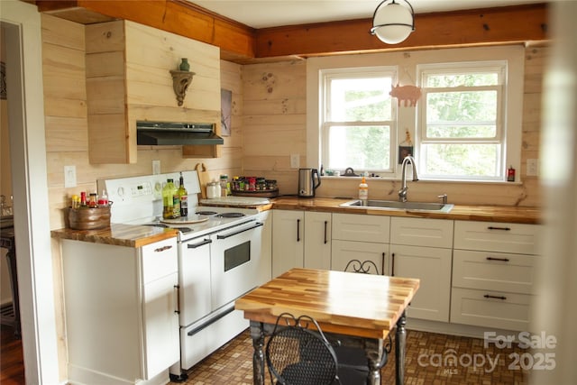 kitchen featuring butcher block countertops, white range with electric cooktop, a sink, and wood walls