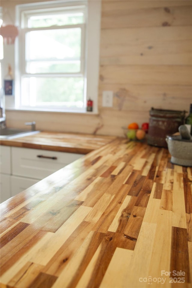 kitchen with butcher block countertops, wood finished floors, and white cabinetry