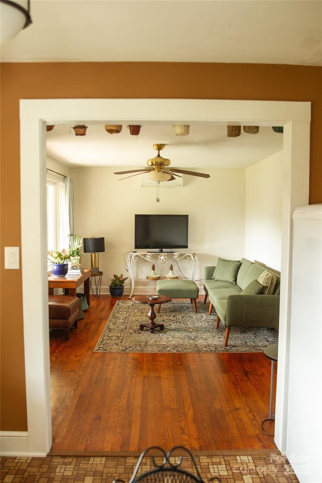 living area with ceiling fan, baseboards, and wood finished floors