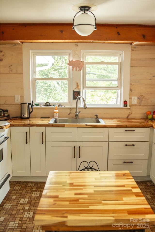 kitchen featuring butcher block countertops, white cabinets, and a sink