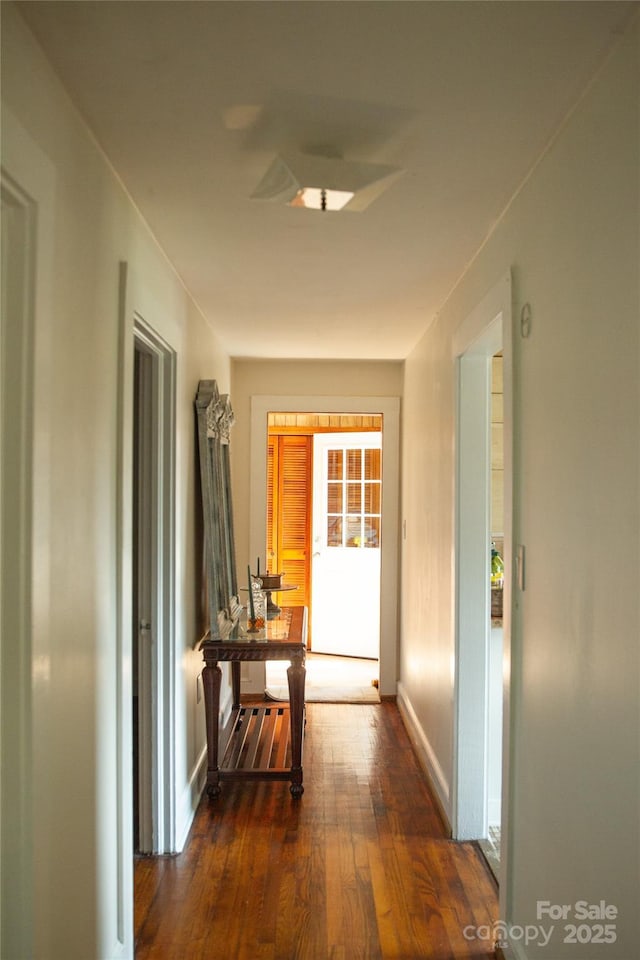 corridor featuring dark wood finished floors and baseboards