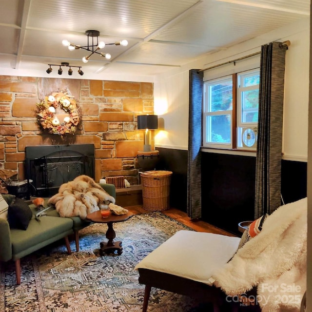 interior space featuring a fireplace, wood finished floors, rail lighting, and an inviting chandelier