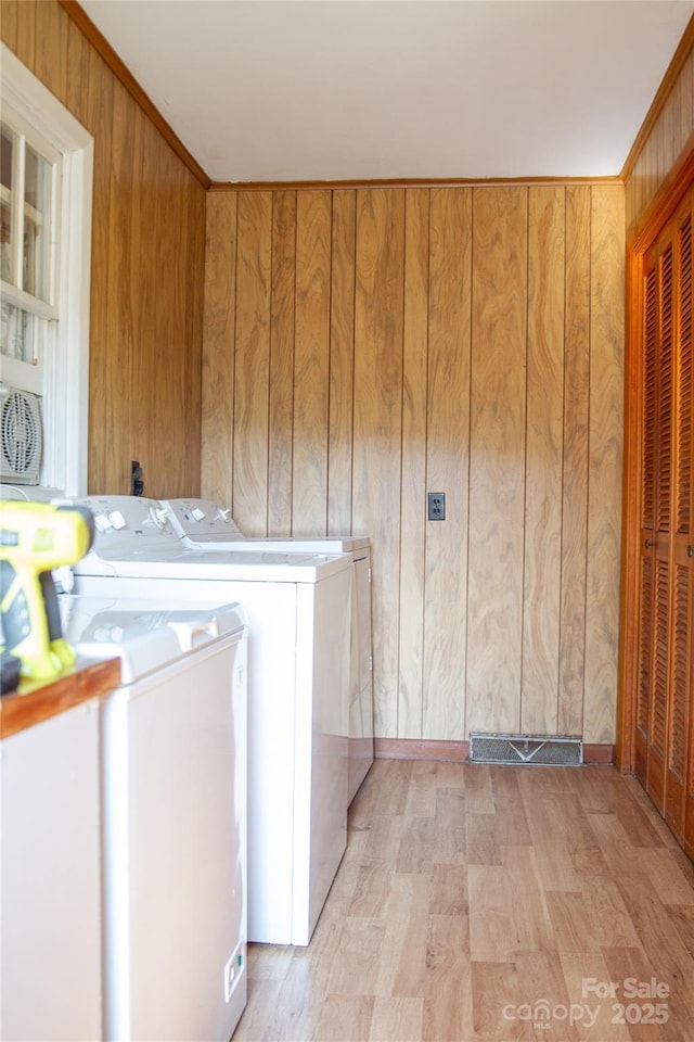 clothes washing area featuring laundry area, visible vents, independent washer and dryer, and wooden walls